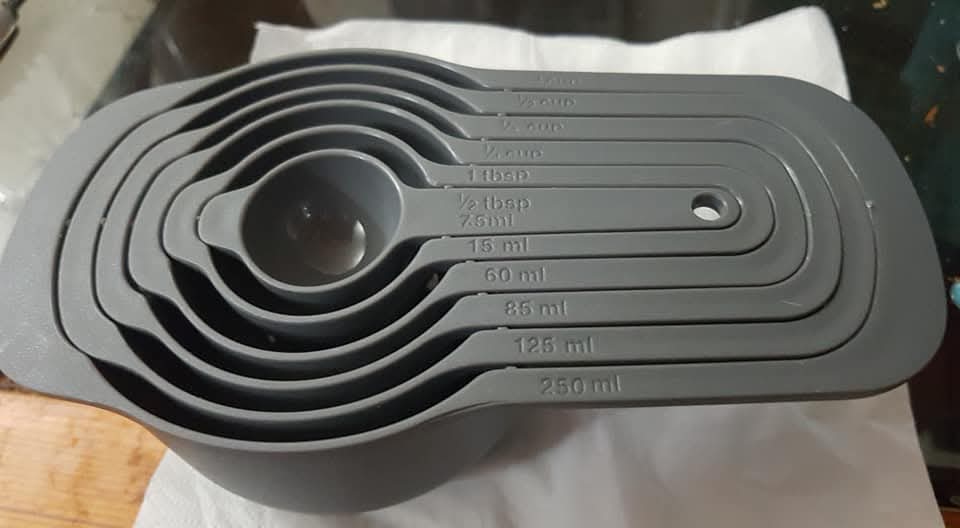 9-piece gray nesting plastic measuring cup and spoon set for kitchen use.