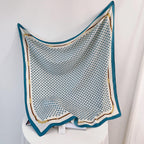 Teal and white silk-satin scarf featuring a monogram pattern and decorative gold chain print