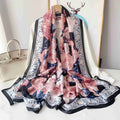 Blush pink silk-satin scarf featuring a large peony floral print on a navy background with a decorative light blue floral border