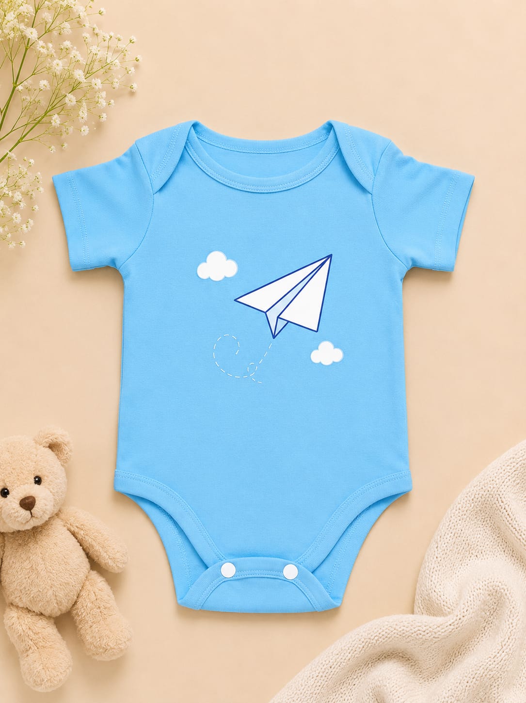 Sky blue short-sleeve baby bodysuit featuring a white paper airplane and cloud graphic by NIFTY.