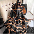 Black silk-satin scarf featuring a bold bronze abstract geometric curved line pattern