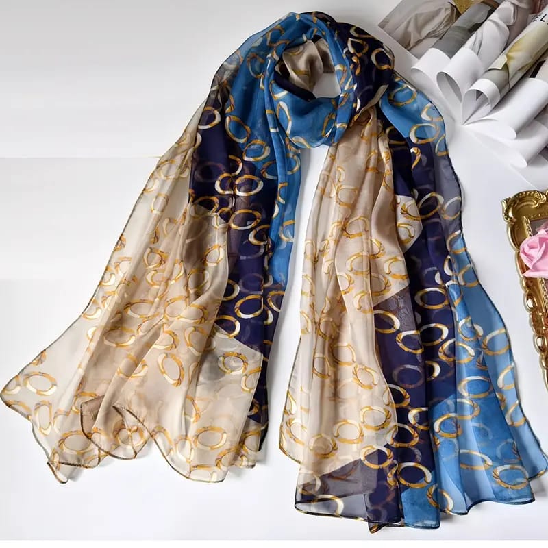 Luxury silk-satin scarf featuring a repeating gold interlocking chain motif on navy blue, teal, and champagne panels