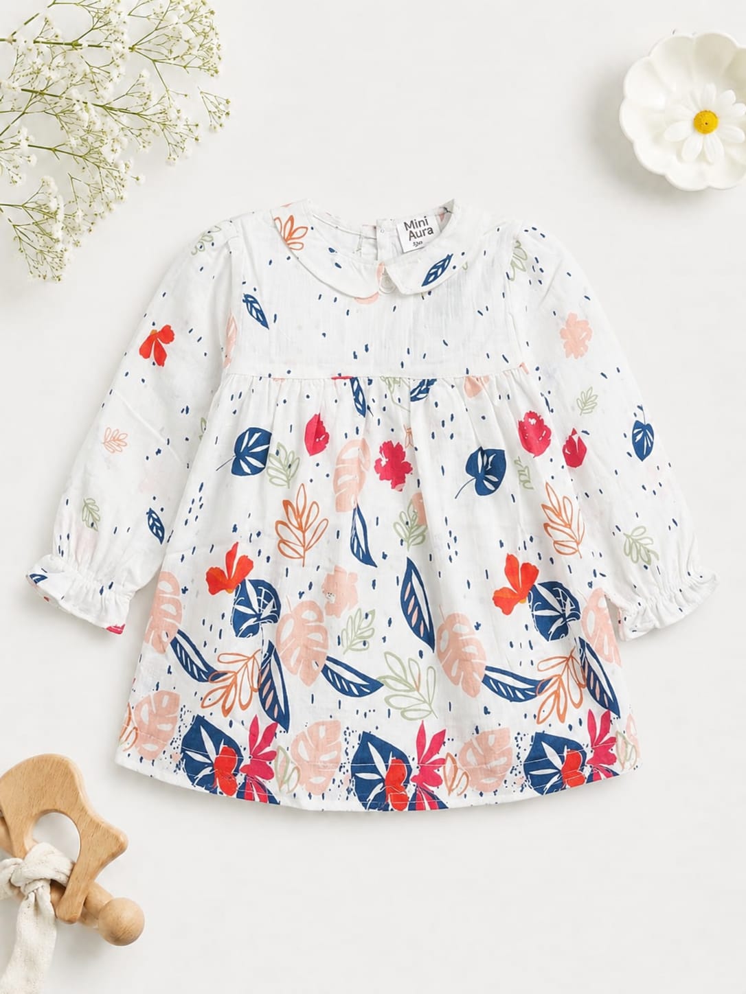 White long-sleeve cotton toddler dress with colorful tropical leaf print.
